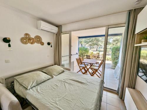 une chambre avec un lit et un balcon avec une table dans l'établissement Les Restanques 2058 rez de jardin, à Grimaud