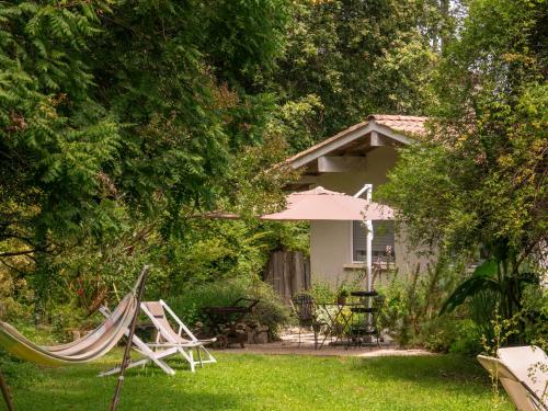une cour avec des chaises et un parasol ainsi qu'une maison dans l'établissement Chambre d'hôtes au calme avec spa, à Nérac