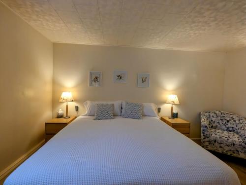 a bedroom with a bed with two lamps and a chair at Fireweed Apartments in Fairbanks