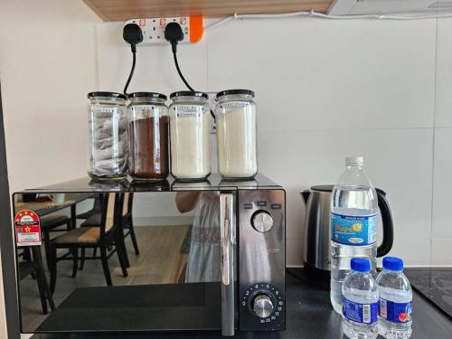 a counter with four glass jars on top of a blender at Kenyalang Roxy Sematan Homestay in Sematan
