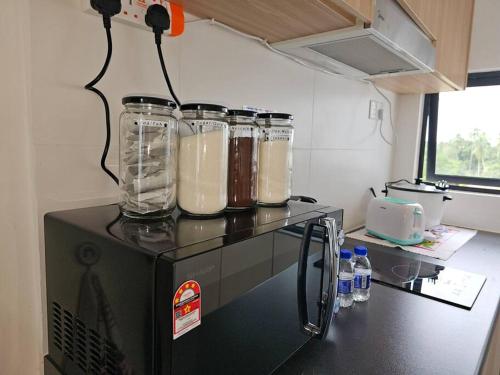 a kitchen with three glass jars on top of a appliance at Kenyalang Roxy Sematan Homestay in Sematan