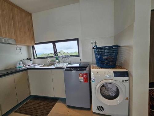 a small kitchen with a washing machine and a sink at Kenyalang Roxy Sematan Homestay in Sematan