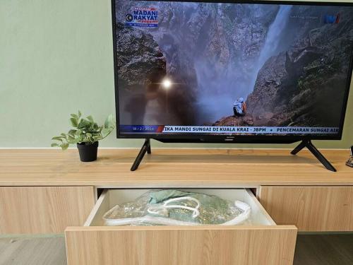 a flat screen tv sitting on top of a wooden cabinet at Kenyalang Roxy Sematan Homestay in Sematan