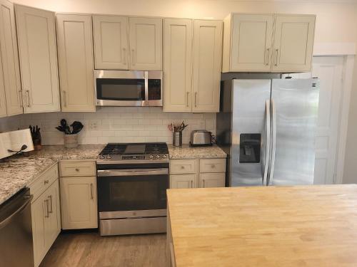a kitchen with white cabinets and a stainless steel refrigerator at The Glarum House - Gorgeous Historic Home & Ac! in Elberta