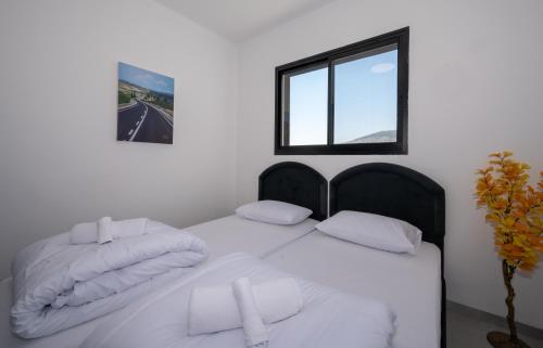 a bedroom with a bed with white sheets and a window at לוי-קיישן מגוון דירות גן ופנטהאוזים וסוויטות נוף ברחוב הצנחנים in Tiberias