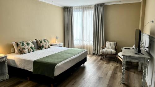 a bedroom with a bed and a desk and a television at Gardi Hotel & Suites in Buenos Aires
