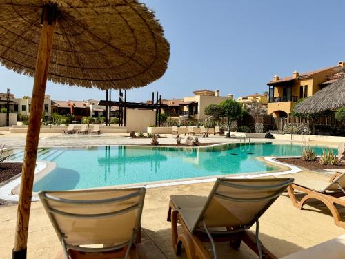 una piscina con dos sillas y una sombrilla en Take It EaSea, en San Miguel de Abona