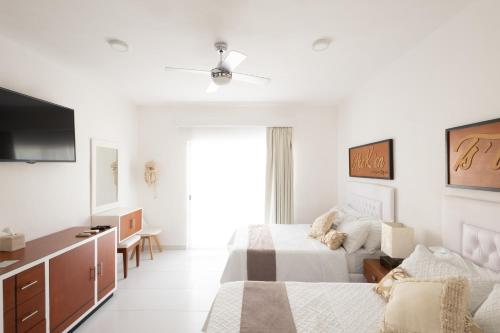 a white bedroom with a bed and a tv at Saastah Hotel Boutique in Valladolid
