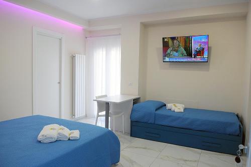 a bedroom with two beds and a tv on the wall at B&B AIDA Rooms Cefalù in Cefalù
