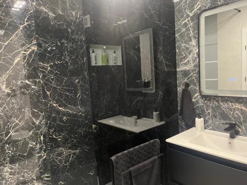a black marble bathroom with a sink and a mirror at Apartament Prima Arena in Oradea