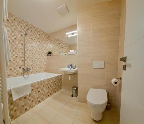 a bathroom with a toilet and a tub and a sink at Apartment Holata 401 in Hradec Králové