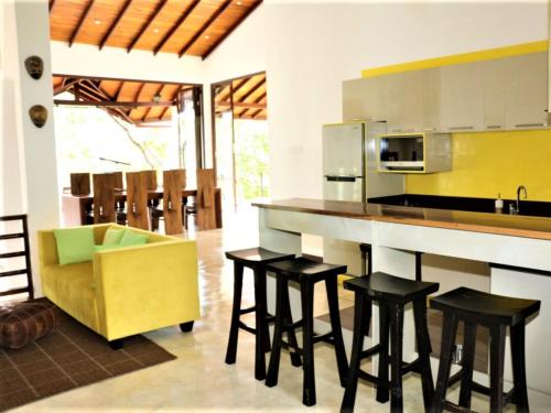 a kitchen with a bar with stools and a yellow chair at Aqua Dunhinda Villa in Kandy