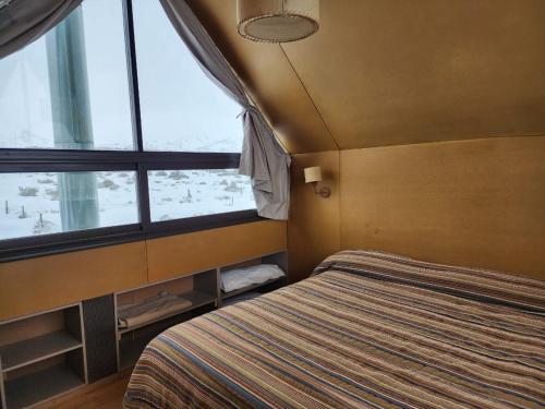 a bedroom with a bed and a large window at Pueblo Andino in Malargüe