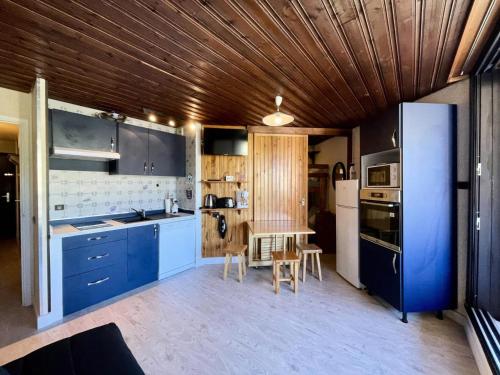 Il comprend une cuisine avec des placards bleus et un plafond en bois. dans l'établissement Résidence Serac - VAL THORENS location: Confortable studio pour 4 pers, dans le haut de la station MAE-9117, à Val Thorens