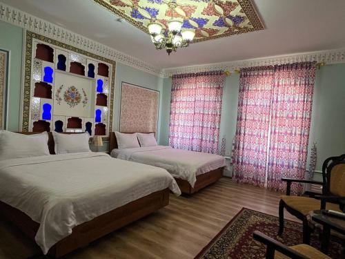 een slaapkamer met 2 bedden en een kroonluchter bij Grand Emir Residence in Bukhara