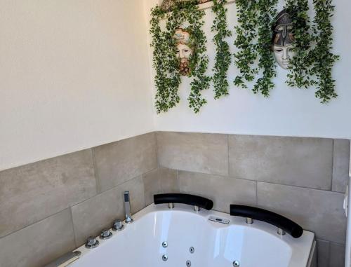 a bath tub in a bathroom with plants on the wall at Alema apartment Giardini Naxos in Giardini Naxos