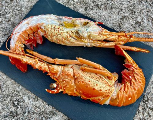 a lobster sitting on a blue cutting board at LOGIS HÔTEL, CHALETS et RESTAURANT LES CHATELMINÉS in La Bresse