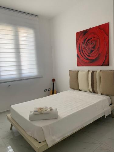 a bed in a white room with a painting on the wall at B&B Passione Salento in Surbo