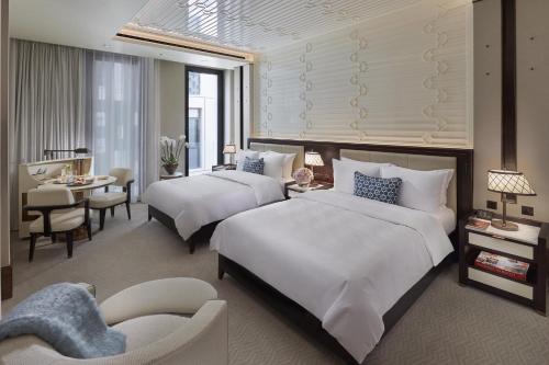 a hotel room with two beds and a dining room at Mandarin Oriental, Doha in Doha