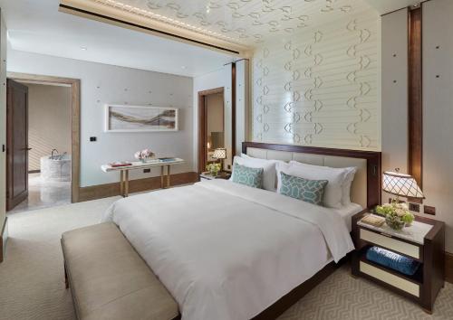 a bedroom with a large white bed and a table at Mandarin Oriental, Doha in Doha