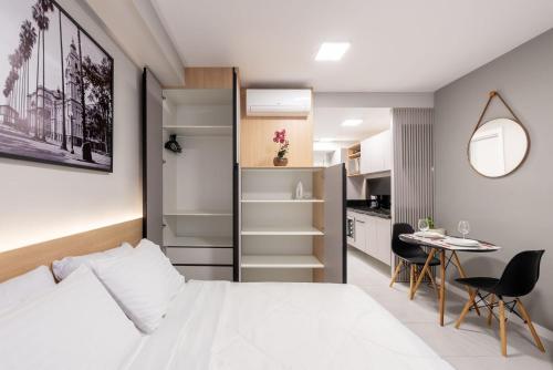 a bedroom with a bed and a table and a kitchen at Connect by LikeHome in Porto Alegre
