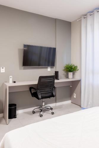 an office with a desk with a chair and a television at Connect by LikeHome in Porto Alegre