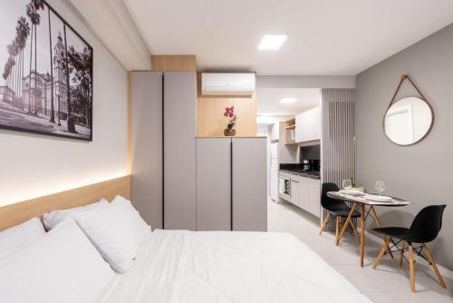 a bedroom with a bed and a table and a kitchen at Connect by LikeHome in Porto Alegre