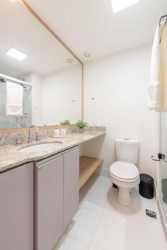 a white bathroom with a toilet and a sink at Connect by LikeHome in Porto Alegre