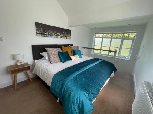 a bedroom with a large bed with blue sheets at The Upton Coach House in Birkenhead