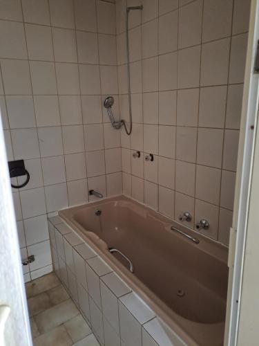 a bath tub in a bathroom with white tiles at Randhart guesthouse in Alberton