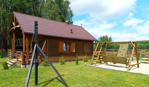a small wooden cabin with a swing in the yard at Leśne Zacisze domki letniskowe in Lipnica