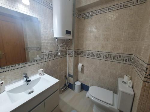 een badkamer met een wastafel, een toilet en een spiegel bij El balcón de Nerja in Nerja