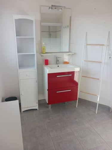 La salle de bains est pourvue d'un lavabo et d'une armoire rouge. dans l'établissement Mas la Daune, à Le Cailar