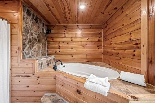 a bathroom with a tub in a wooden wall at Pvt Pool at The Grotto in Sevierville