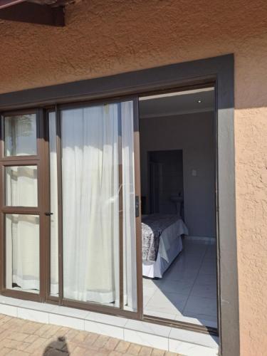 a sliding glass door of a house with a bedroom at Randhart guesthouse in Alberton