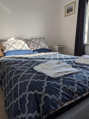 a bed with a blue and white blanket and pillows at Lovely 3-Bed Edinburgh Flat in Edinburgh