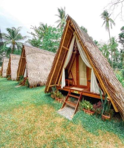 a group of huts with a grass roof at TLT Guesthouses - Dauin in Dauin