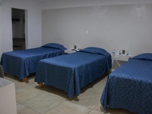 a room with three beds with blue covers on them at Hotel St. George in Celaya
