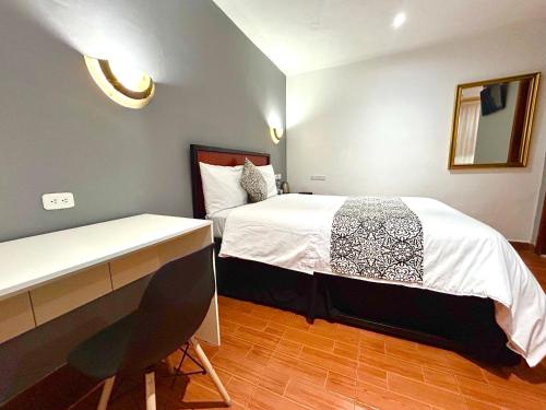 a bedroom with two beds and a desk in it at ACCEL Hotel La Quinta in Ibarra