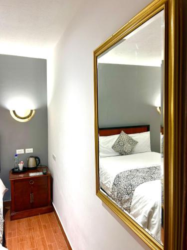 a bedroom with a mirror and a bed with white sheets at ACCEL Hotel La Quinta in Ibarra