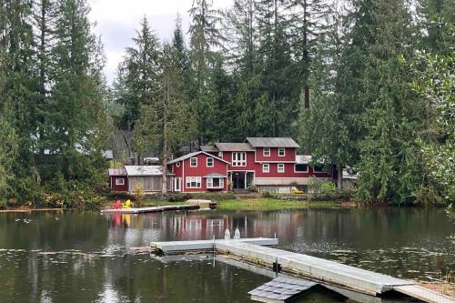 a red house on a lake with a dock at Palace Under the Pines in Bow