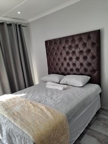 a bedroom with a large bed with a padded headboard at Randhart guesthouse in Alberton
