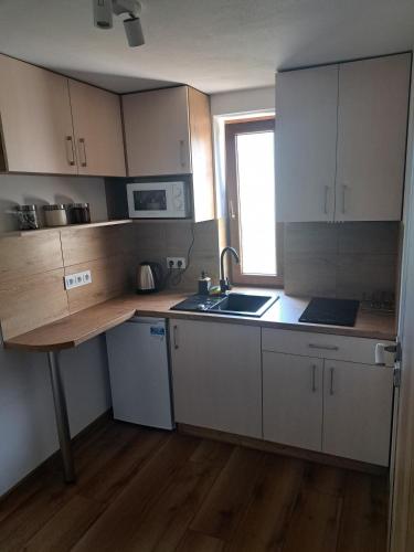 a kitchen with white cabinets and a sink and a window at Agroturystyka Oblica in Zawoja