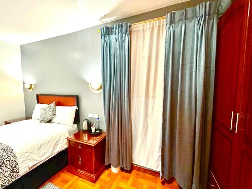 a bedroom with a bed and a window with curtains at ACCEL Hotel La Quinta in Ibarra