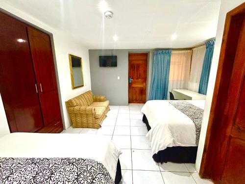 a hotel room with two beds and a chair at ACCEL Hotel La Quinta in Ibarra