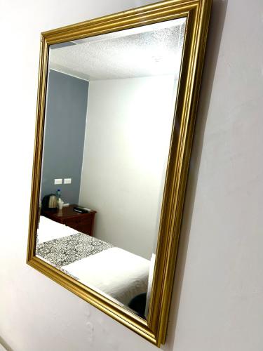 a gold framed mirror on a wall in a bedroom at ACCEL Hotel La Quinta in Ibarra