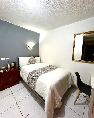 a bedroom with a bed and a mirror and a chair at ACCEL Hotel La Quinta in Ibarra