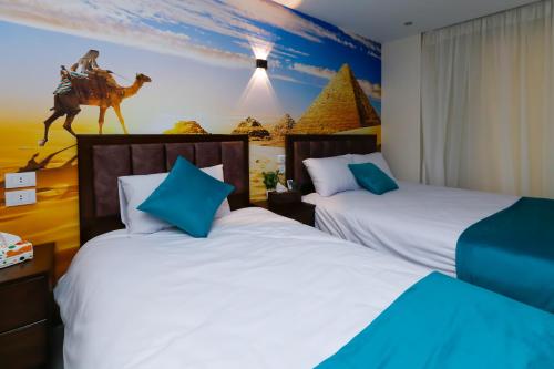 a room with two beds and a painting of a camel at Diamond Pyramids View Inn in Cairo