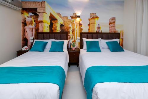 two beds in a hotel room with blue pillows at Diamond Pyramids View Inn in Cairo