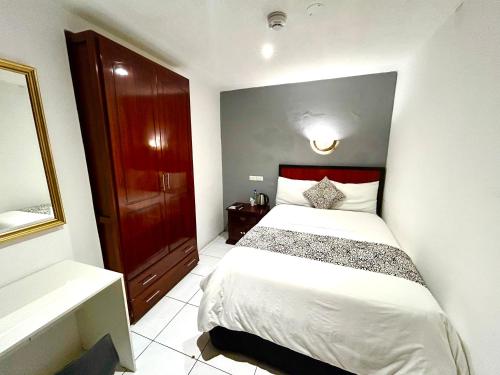 a bedroom with a white bed with a red headboard at ACCEL Hotel La Quinta in Ibarra